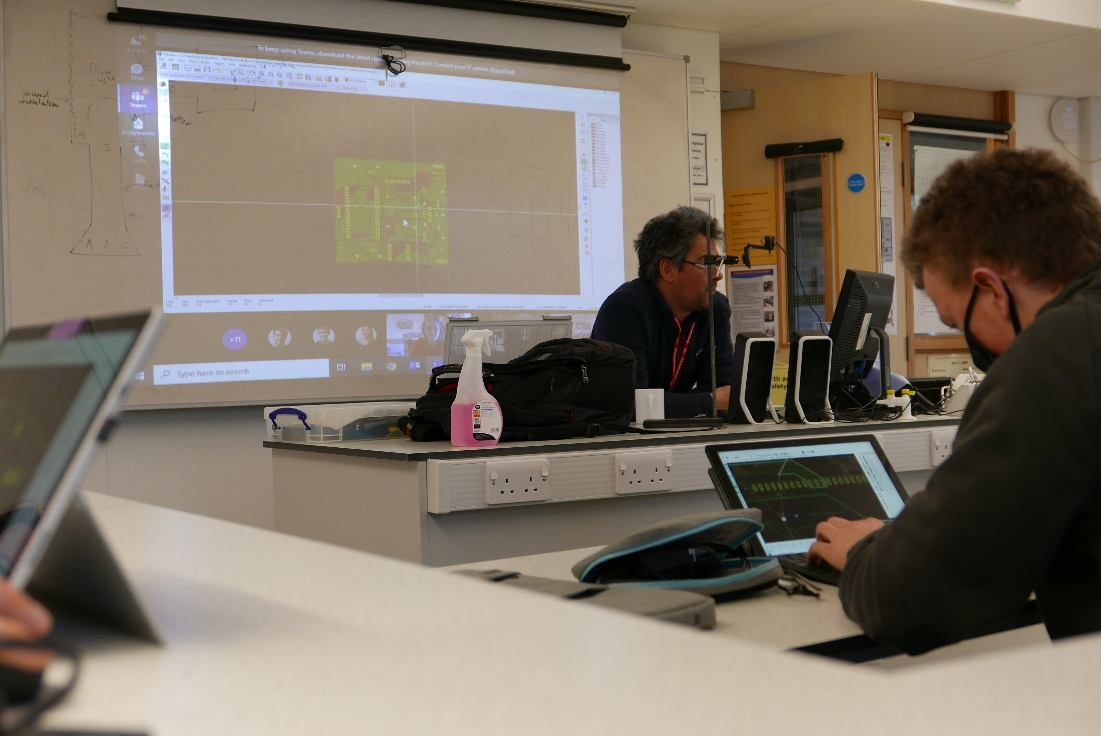 An image of a William working on his PCB with Will debugging another one